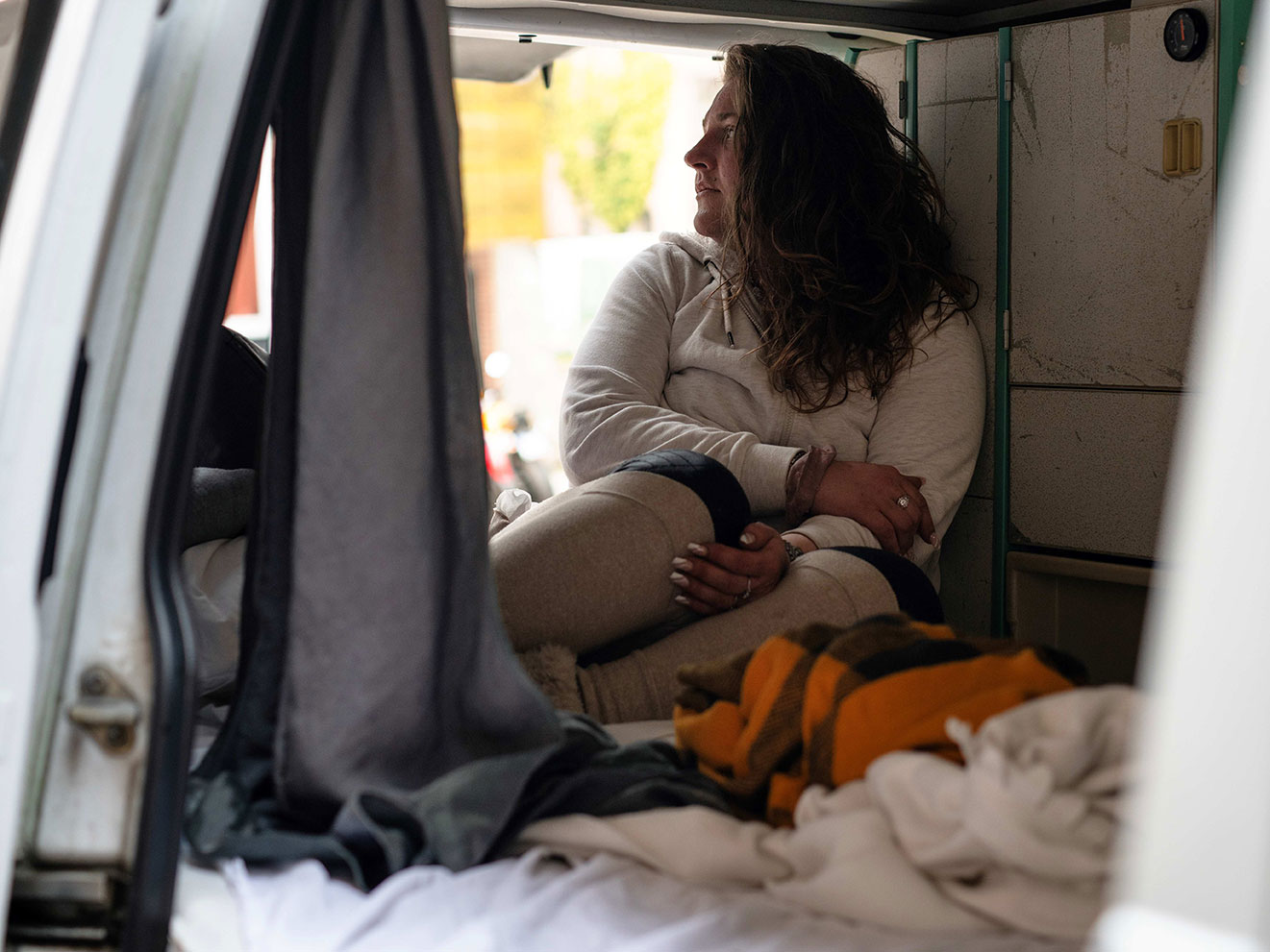 Vrouw zit in een busje met dekens en laken